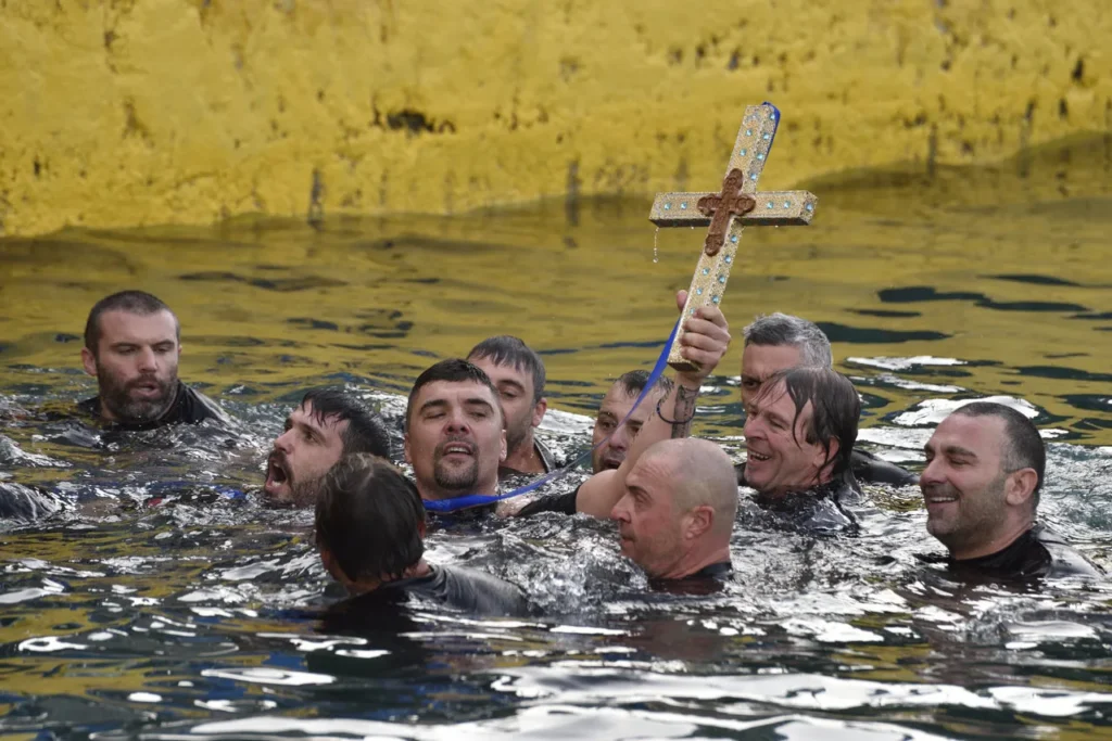 man retrieves the cross from the sea during the blessing of the waters on epiphany day in greece